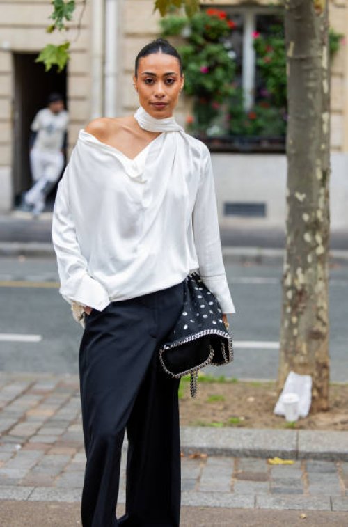 Guest wears black white bag, pants, white blouse outside Stella McCartney during Womenswear Spring/Summer 2025 as part of Paris Fashion Week on...
