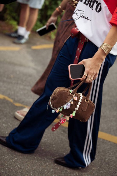 Guest wears blue adidas pants, Marlboro red and white shirt and brown Miu Miu bag with accessories outside the vision show during day two of the...