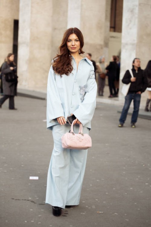 Guest wears blue pants, button-up shirt or blouse and pink bag outside the Georges Hobeika fashion show during the Womenswear Fall/Winter 2025/2026...