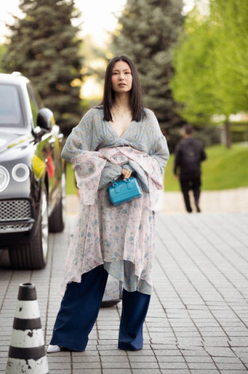 Guest wears blue wide pants, blue bag and light pink silk dress on day 2 of Visa Fashion Week Almaty 2024 on May 02, 2024 in Almaty, Kazakhstan.