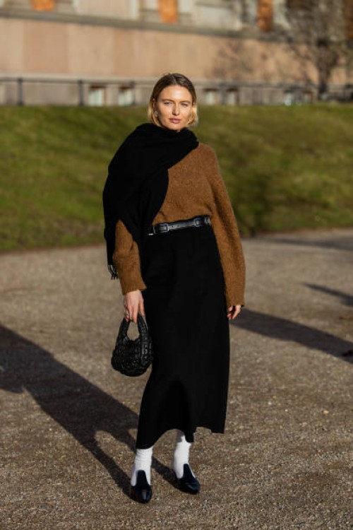 Guest wears brown knit, black scarf, black bag, high waisted shirt, white socks, heels outside Marimekko during the Copenhagen Fashion Week AW24 on...