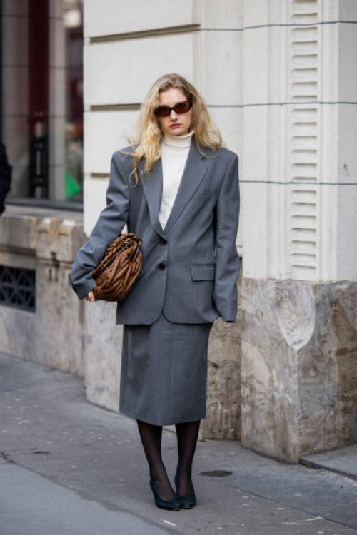 Guest wears brown Miu Miu bag, grey suit outside Magda Butrym presentation during the Womenswear Fall/Winter 2025/2026 as part of Paris Fashion Week...