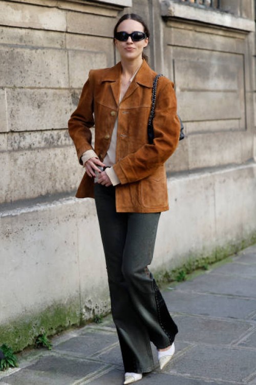Guest wears brown suede jacket, dark grey jeans, black sunglasses, outside Nina Ricci, during the Womenswear Fall/Winter 2025/2026 as part of Paris...