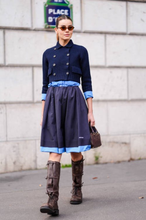 Guest wears brown sunglasses, a blue knitted jacket, a blue Miu Miu midi skirt, brown leather Miu Miu bag, brown boots, outside Miu Miu, during the...