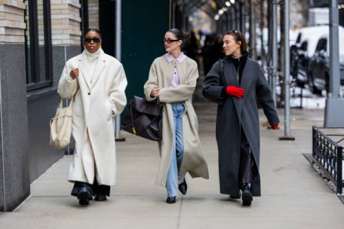 Guest wears creme white oversized coat & a guest black bag, coat & a guest wears grey coat, red gloves outside Ulla Johnson during New York Fashion...