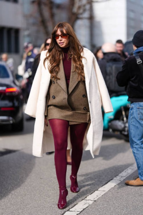 Guest wears dark brown sunglasses, burgundy bordeaux turtleneck long sleeve shirt, dark brown double breasted belted Ferragamo jacket, cream coat,...