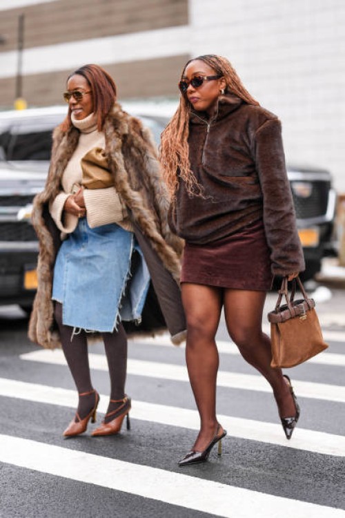 Guest wears dark brown sunglasses, cream turtleneck oversized sweater, light brown faux fur coat, light brown leather bag, light blue high slit denim...