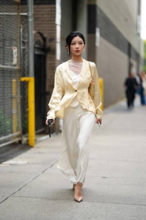 Guest wears earrings, a white lustrous dress with mesh / lace and floral embroidery, a pale pastel yellow silk lustrous cardigan, pointed shoes,...