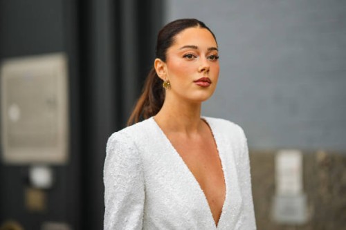 Guest wears gold earrings, a white embroidered sequined V-neck / shoulder-pads / blazer jacket, during New York Fashion Week, on September 11, 2022...