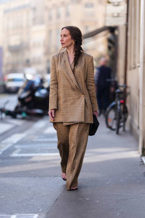 Guest wears gold earrings, dark orange light gray pattern/print linen wrapped oversized The Row Jeremiah blazer jacket, dark orange light gray...