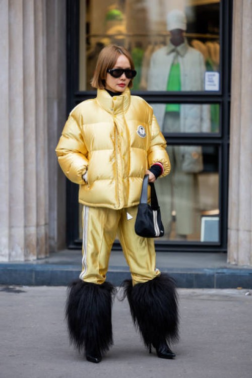 Guest wears golden puffer jacket, jogger pants, faux fur black boots outside Palm Angels Paris Fashion Week - Womenswear Fall Winter 2023 2024 : Day...