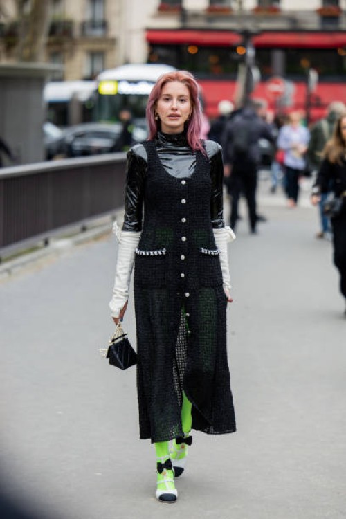 Guest wears green black button up transparent dress, neon green tights, black bag outside Chanel during the Womenswear Fall/Winter 2024/2025 as part...