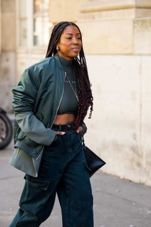 Guest wears green cropped top, bomber jackt, pants with side pockets outside Sacai during the Womenswear Fall/Winter 2024/2025 as part of Paris...