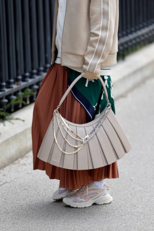 Guest wears green Lacoste printed long top, cream cardigan, beige Lacoste jacket, brown pleated maxi skirt, beige Lacoste bag, beige Lacoste...
