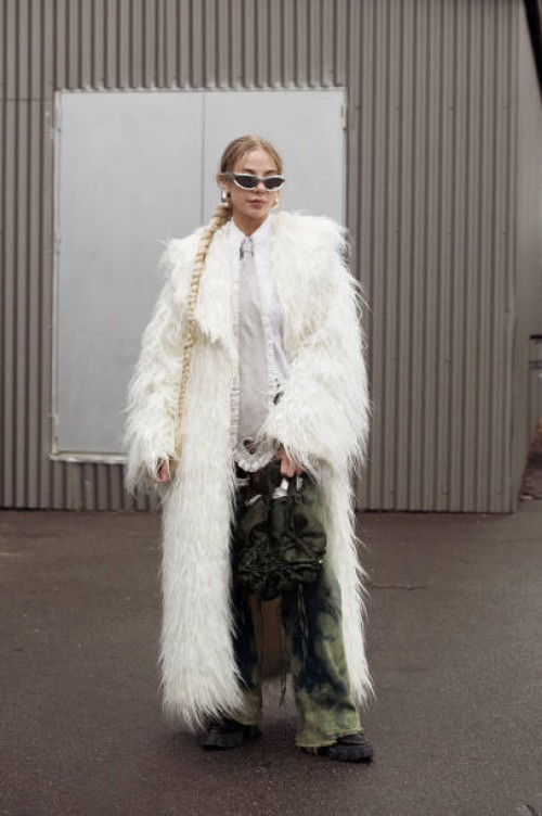 Guest wears green pants, a white shirt, a grey tie with cut out heart, and an army green bag outside Vain during the Copenhagen Fashion Week AW24 on...
