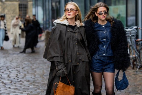 Guest wears grey coat & a guest wears denim shorts, shirt, black fur jacket outside Munthe during the Copenhagen Fashion Week Autumn/Winter 2025 on...