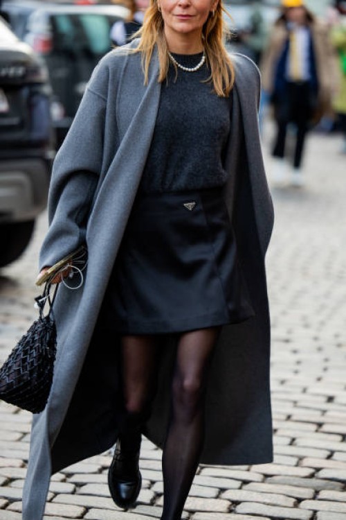 Guest wears grey coat, black Prada skirt, tights, knit outside Nicklas Skovgaard during the Copenhagen Fashion Week AW24 on January 29, 2024 in...