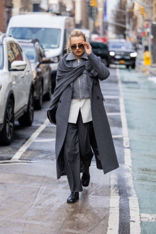 Guest wears grey coat, zipper, pants outside Michael Kors on February 13, 2024 in New York City.