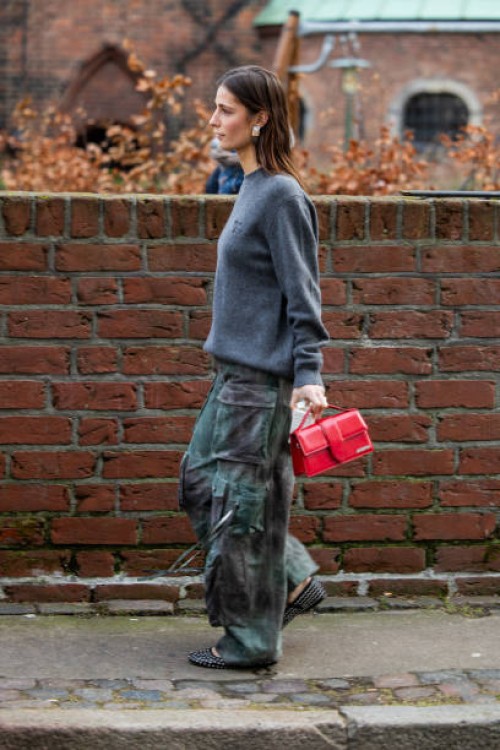 Guest wears grey knit, red Jacquemus bag, camouflage pants with side pockets outside Nicklas Skovgaard during the Copenhagen Fashion Week AW24 on...