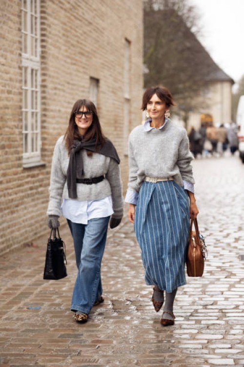 Guest wears grey sweater with black belt, blue jeans, animal print shoes and black bag with accessories and a guest wears grey sweater, blue denim...