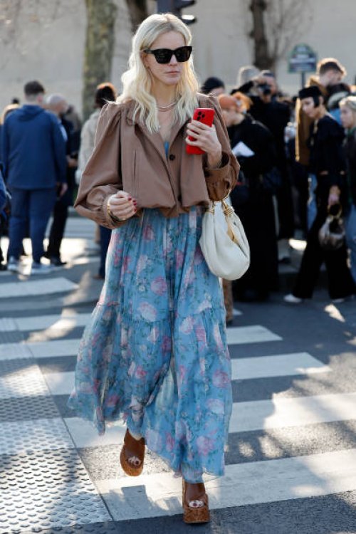 Guest wears light blue floral print maxi dress, beige Chloé bag, brown crop jacket, brown wedge shoes, outside Chloé, during the Womenswear...