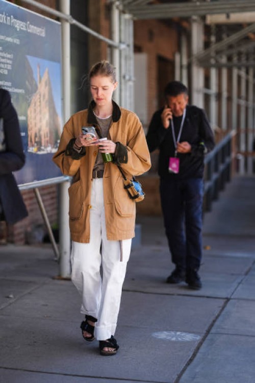 Guest wears light brown oversized jacket, light gray sweater, dark brown leather belt, white denim jean cuffed pants, black light brown leather...