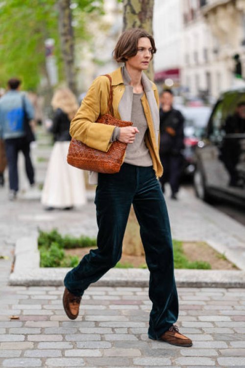 Guest wears light gray t-shirt, light gray cropped jacket, dark yellow cardigan sweater, dark yellow leather cropped jacket, shiny dark brown leather...
