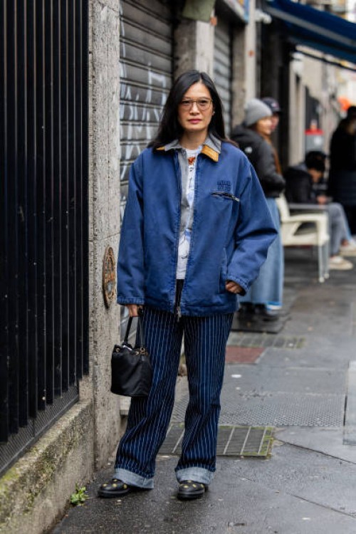 Guest wears Miu Miu blue jacket, striped jeans, black bag outside Magliano during the Milan Fashion Week Menswear Fall/Winter 2025-2026 on January...