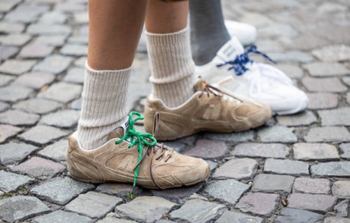 Guest wears New Balance brown sneakers, white socks outside Miu Miu during the Womenswear Fall/Winter 2025/2026 as part of Paris Fashion Week on...