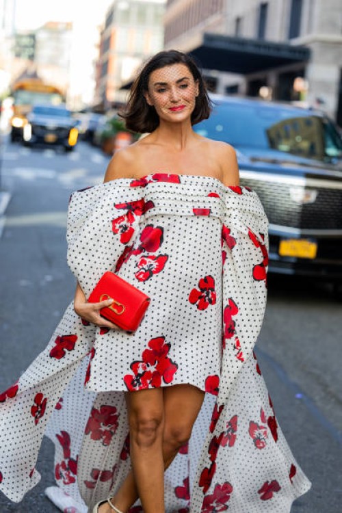 Guest wears off shoulder wide dress with dots and floral print outside Carolina Herrera on September 12, 2023 in New York City.