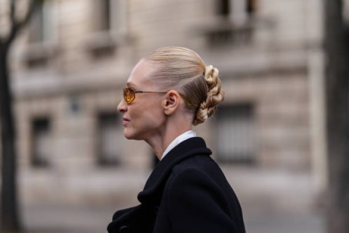 Guest wears orange sunglasses. White loose shirt, white loose over the knee skirt, black coat, outside Miu Miu, during the Paris Fashion Week...
