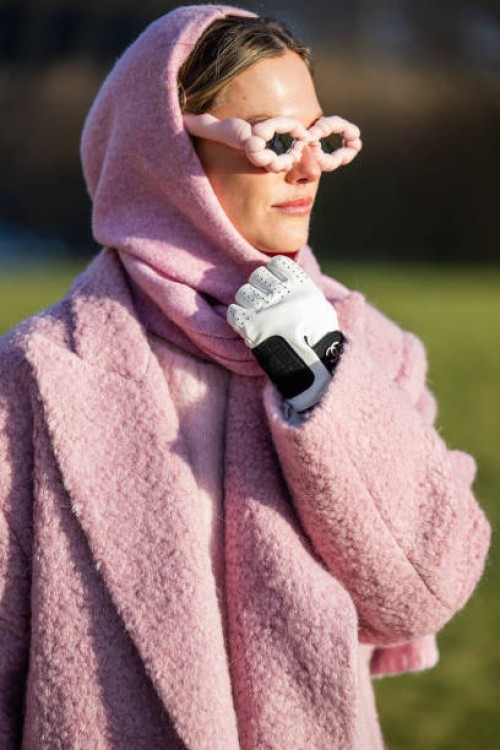 Guest wears pink coat, scarf, jumper, sunglasses, Chanel gloves outside Marimekko during the Copenhagen Fashion Week AW24 on February 01, 2024 in...