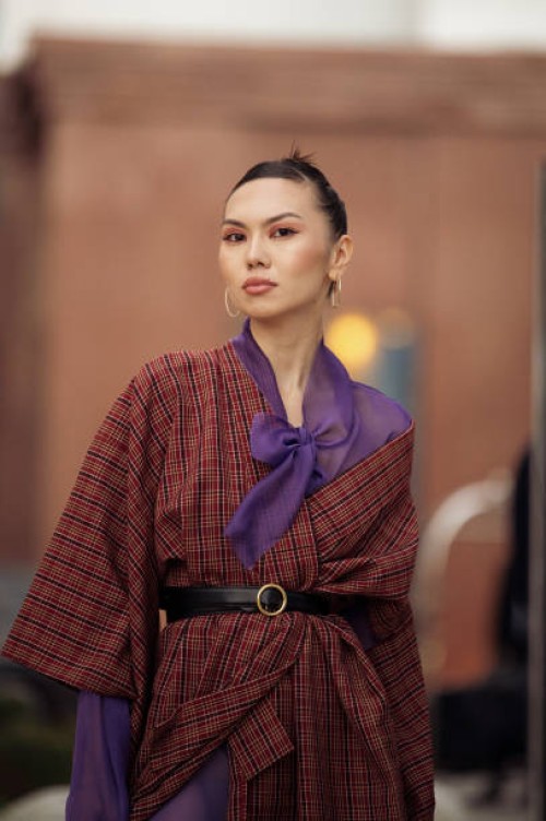 Guest wears purple tights, a brown long coat, and black long leather boots during the Tashkent Fashion Week 2023 on November 27, 2023 in Tashkent,...