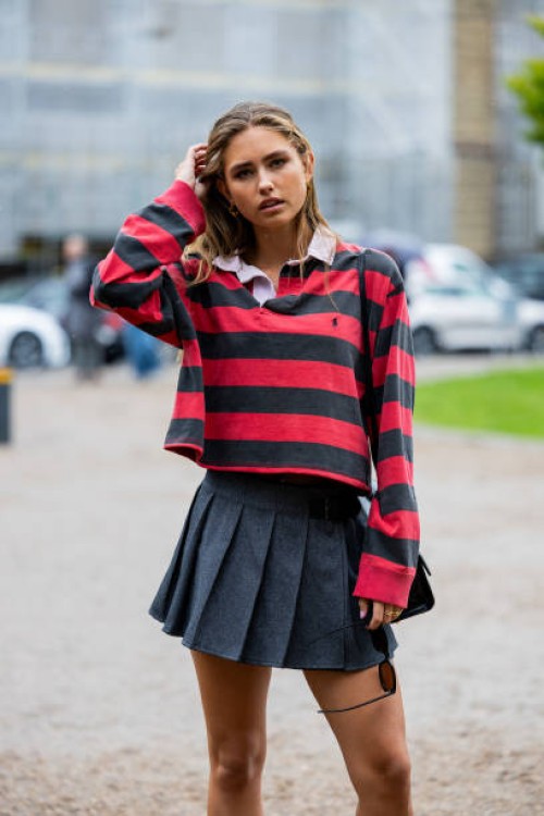 Guest wears red black striped polo with long sleeves, grey pleated mini skirt outside OpéraSport during the Copenhagen Fashion Week Spring/Summer...