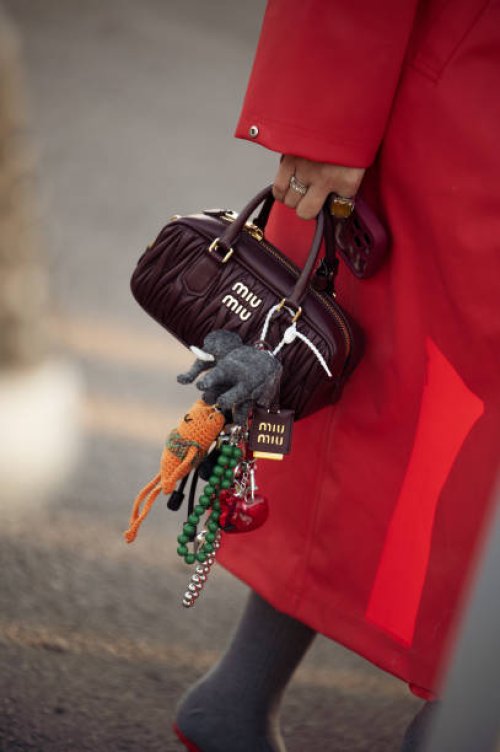 Guest wears red coat and brown Miu Miu bag with accessories during the 10th season of the Visa Fashion Week Almaty on October 18, 2024 in Almaty,...