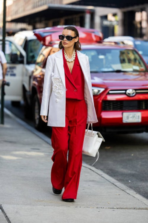 Guest wears red suit, white blazer, bag outside Carolina Herrera on September 12, 2023 in New York City.