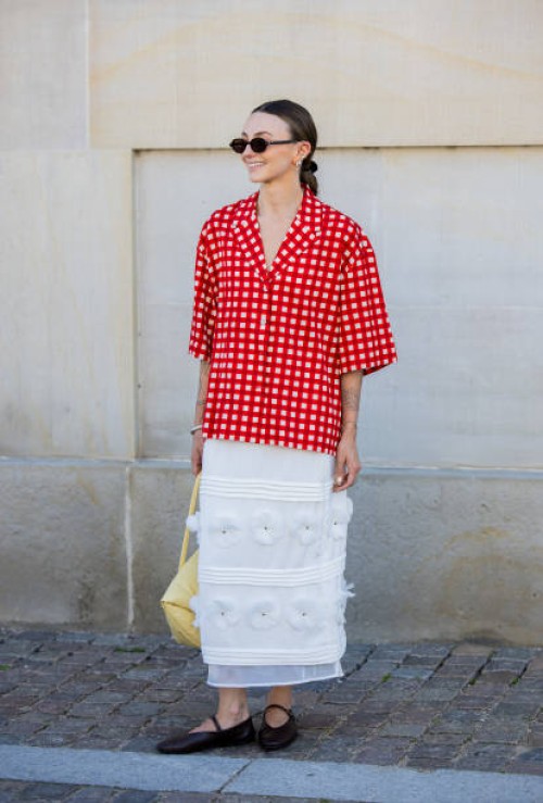 Guest wears red white checkered button shirt, white skirt outside Lovechild 1979 during day two of the Copenhagen Fashion Week SS25 on August 06,...