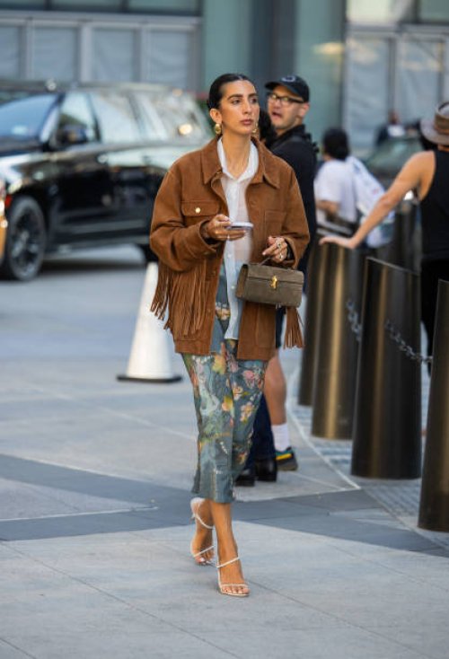 Guest wears Savette bag, brown fringed wild leather jacket outside Michael Kors during New York Fashion Week on September 10, 2024 in New York City.