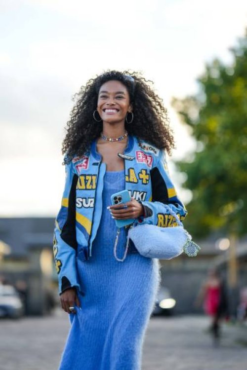 Guest wears silver earrings, a multicolored crystals necklace, a blue wool long dress, a blue shiny leather with yellow and white embroidered pattern...