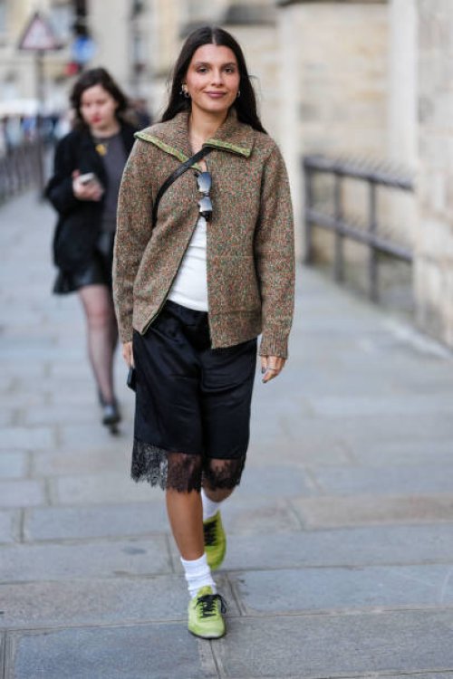 Guest wears silver earrings, dark brown pattern oversized unzipped cardigan jacket, white top, black sunglasses in top, shiny black crossbody leather...