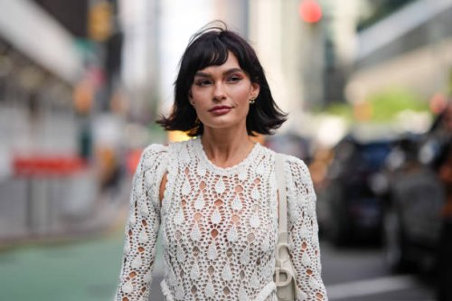 Guest wears silver earrings, white sheer mesh long sleeve tassel Aknvas Willow crochet dress, white Christian Dior Saddle leather bag, silver rings,...