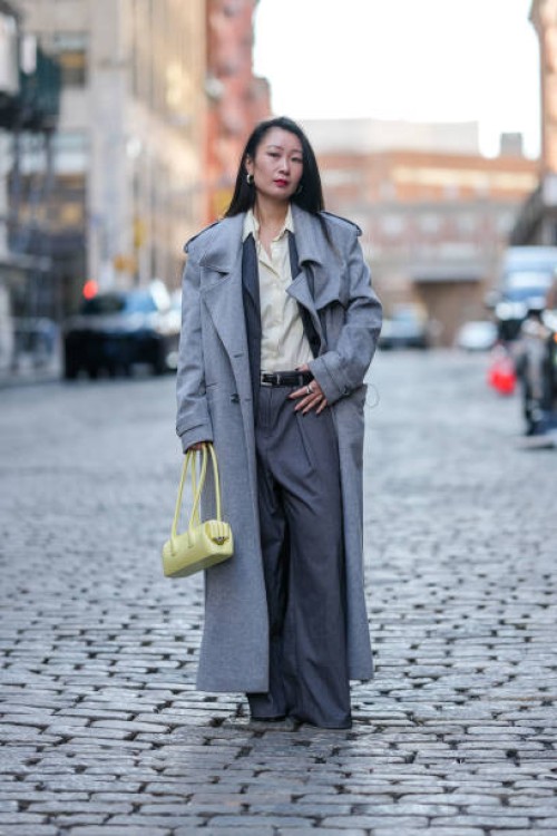 Guest wears silver hoop earrings, light pale yellow buttoned up long sleeve shirt, gray blazer jacket, light gray trench coat, light yellow leather...