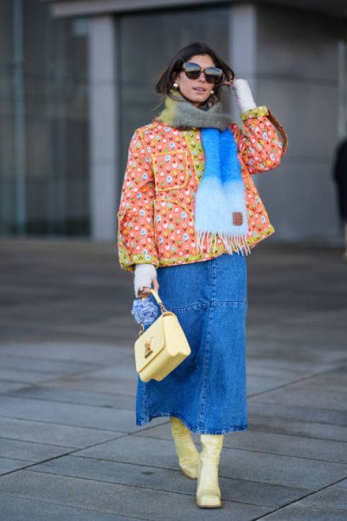 Guest wears sunglasses, a khaki / gray / blue wool fringed scarf, an orange floral print padded jacket with yellow lines, a pastel pale Vuitton bag,...