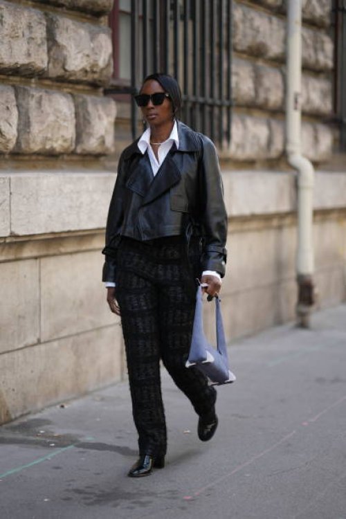 Guest wears sunglasses, a white shirt, a black leather jacket, black pants, a mauve bag, leather shiny shoes, outside Hermes, during the Womenswear...