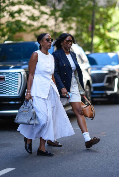 Guest wears sunglasses, a white sleeveless top, a white skirt, a gray Balenciaga bag, outside Toteme, during New York Fashion Week, on September 10,...