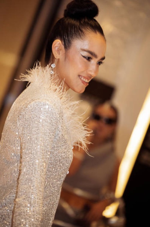 Guest wears white sequin pants, and cropped top with white feathers and a white mini bag during the Tashkent Fashion Week 2023 on November 27, 2023...
