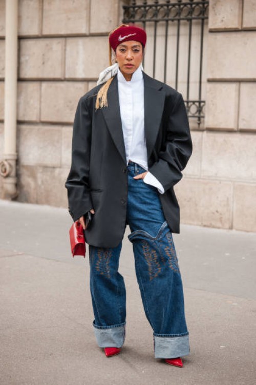 Guest wears white shirt, black blazer, decorated jeans, red heels and bag, red Nike beret, outside Miu Miu, during the Womenswear Fall/Winter...