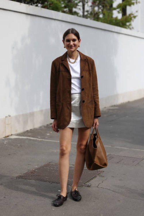 Guest wears white t-shirt, silver mini skirt, brown suade blazer, black loafers, brown tote bag, outside Ferragamo, during the Milan Fashion Week...