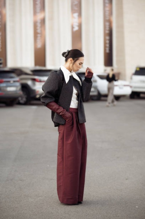 Guest wears wide burgundy pants, white shirt, burgundy leather gloves, grey cropped coat during the 10th season of the Visa Fashion Week Almaty on...