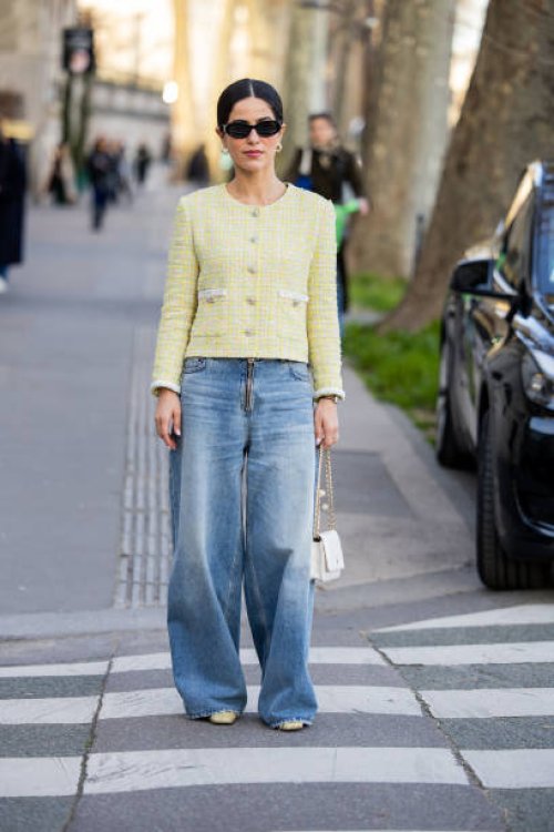 Guest wears yellow button jacket, wide leg denim jeans, white bag outside Rokh during the Womenswear Fall/Winter 2024/2025 as part of Paris Fashion...